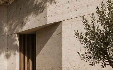 Sunlight and olive shadows across a travertine facade